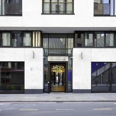 Tower Suites By Blue Orchid London Kültér fotó The image shows the entrance of a modern building, characterized by its minimalist architectural design. The facade features a combination of large glass windows and smooth stone surfaces. The entrance is framed by glass doors, flanked by stylish lig