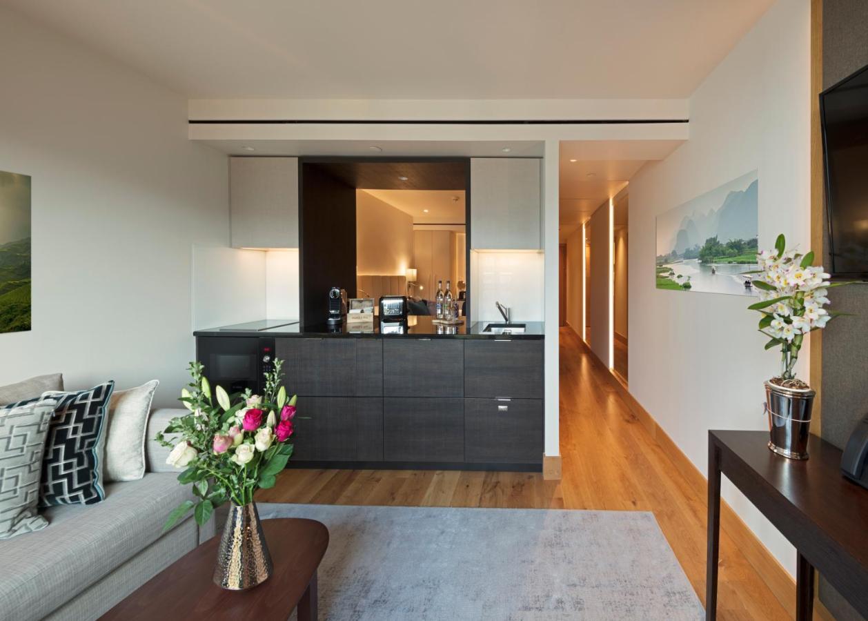 Tower Suites By Blue Orchid London Kültér fotó The photo showcases a modern and stylish interior space, likely a living area of a luxurious apartment or hotel suite. 

- **Bar Area**: There is a sleek bar counter that features a variety of bottles and glassware, suggesting a well-equipped space f