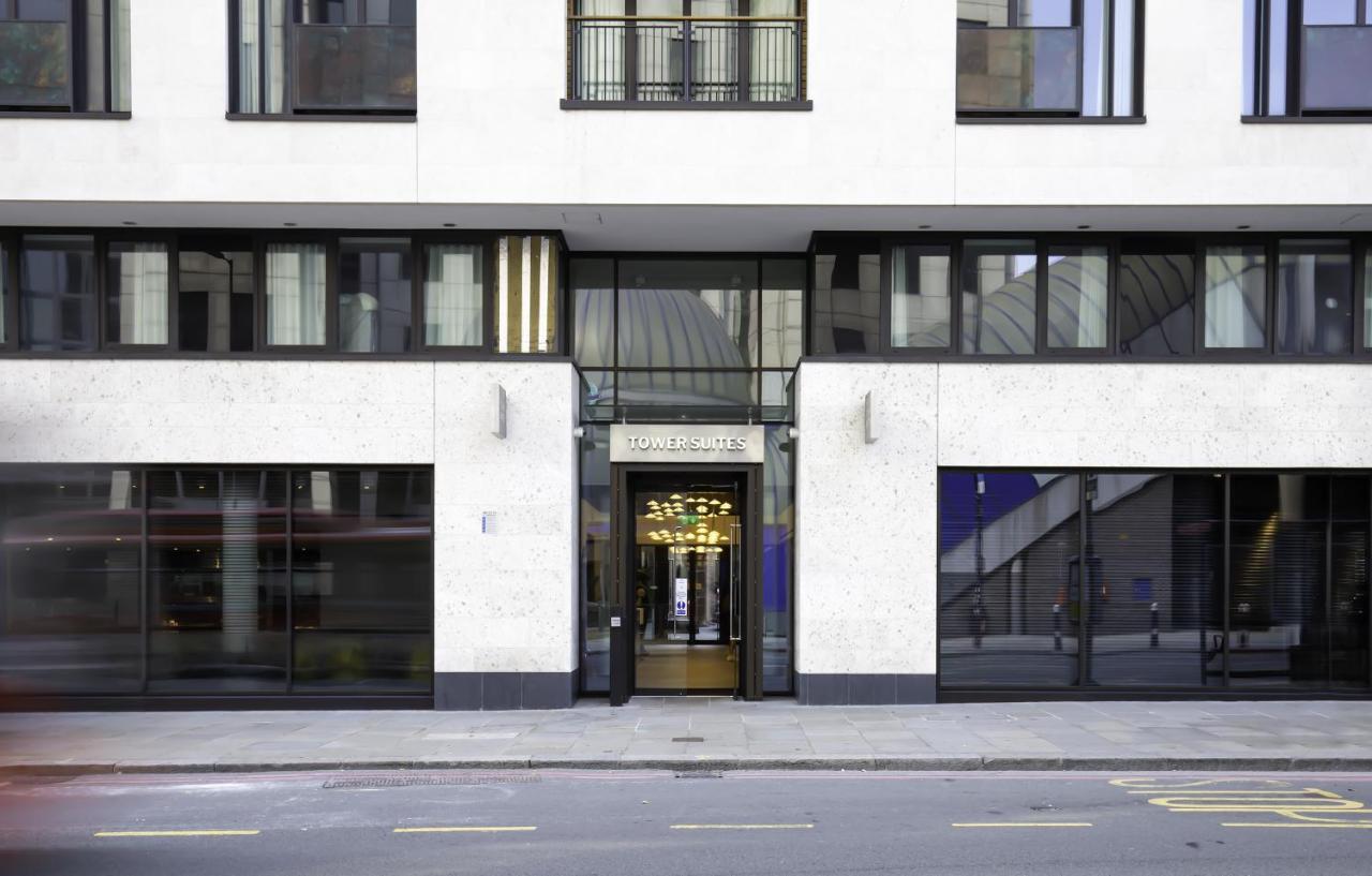 Tower Suites By Blue Orchid London Kültér fotó The image shows the entrance of a modern building, characterized by its minimalist architectural design. The facade features a combination of large glass windows and smooth stone surfaces. The entrance is framed by glass doors, flanked by stylish lig