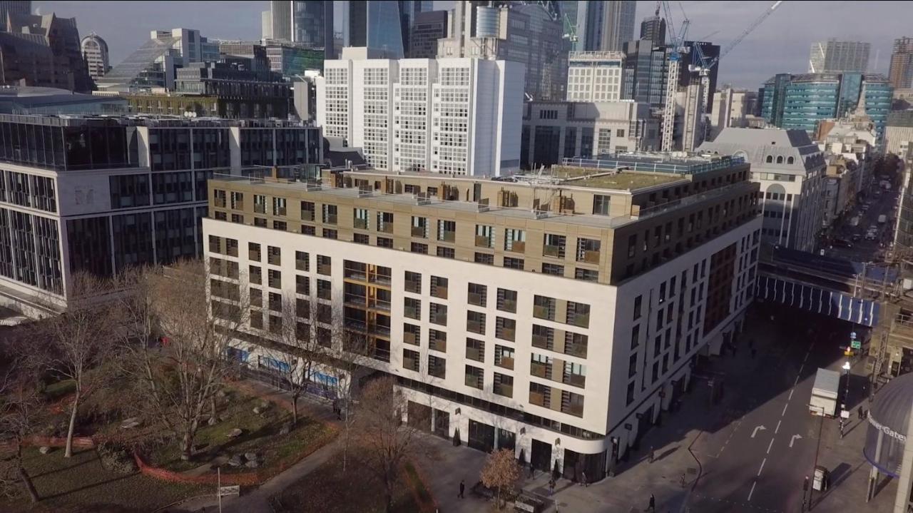 Tower Suites By Blue Orchid London Kültér fotó The photo shows a large, modern building with a combination of white and light-colored facades. The structure has multiple floors and features a series of square windows, providing a contemporary architectural style. Surrounding the building, there a